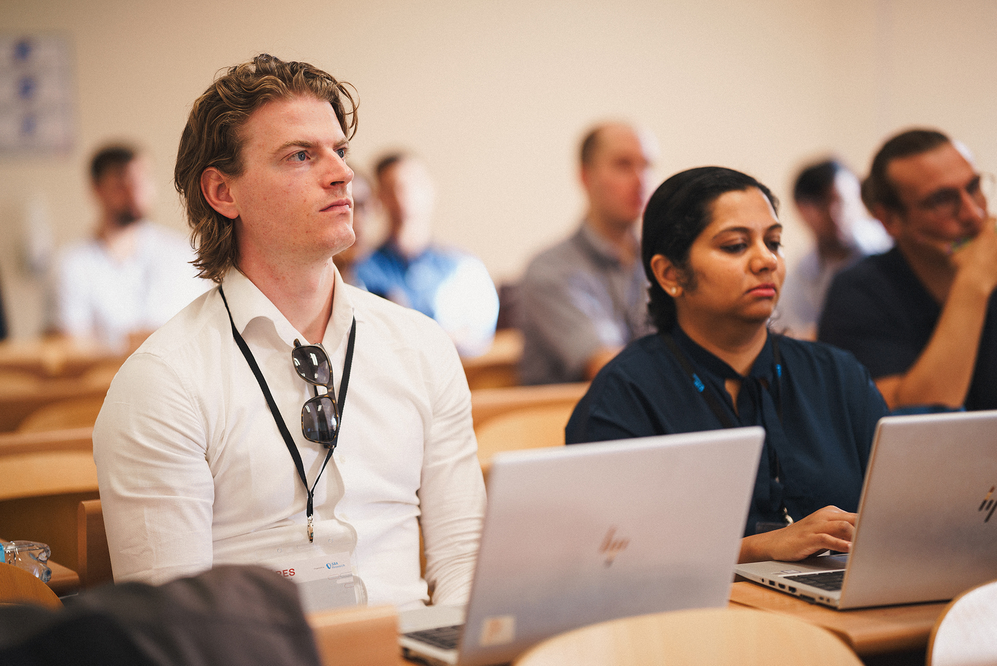 A man and a woman sitting in a classroom with a laptop, engaged in learning and utilizing technology for educational purposes.