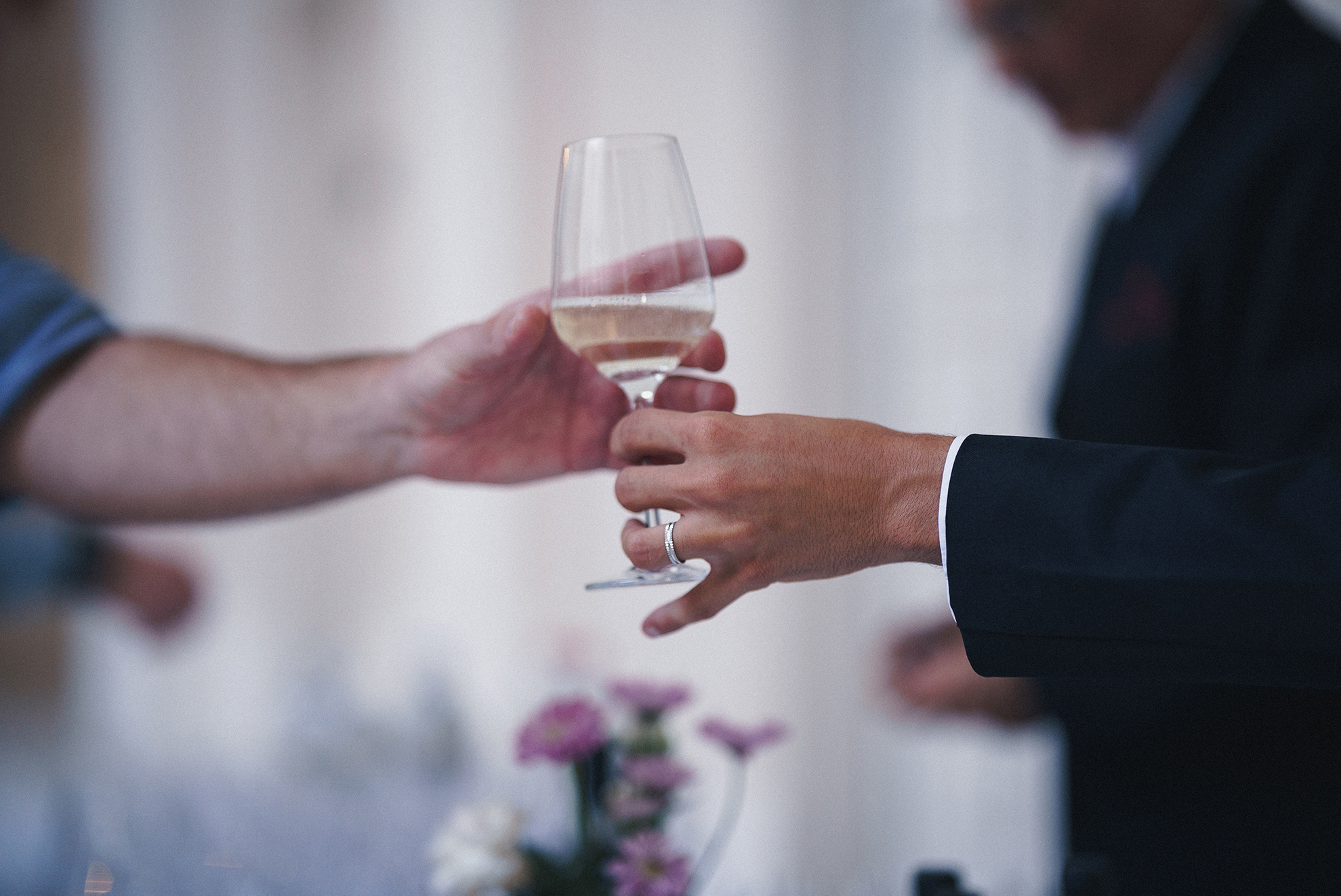 A person gracefully holds a glass of wine, presenting it to another person with elegance and charm.